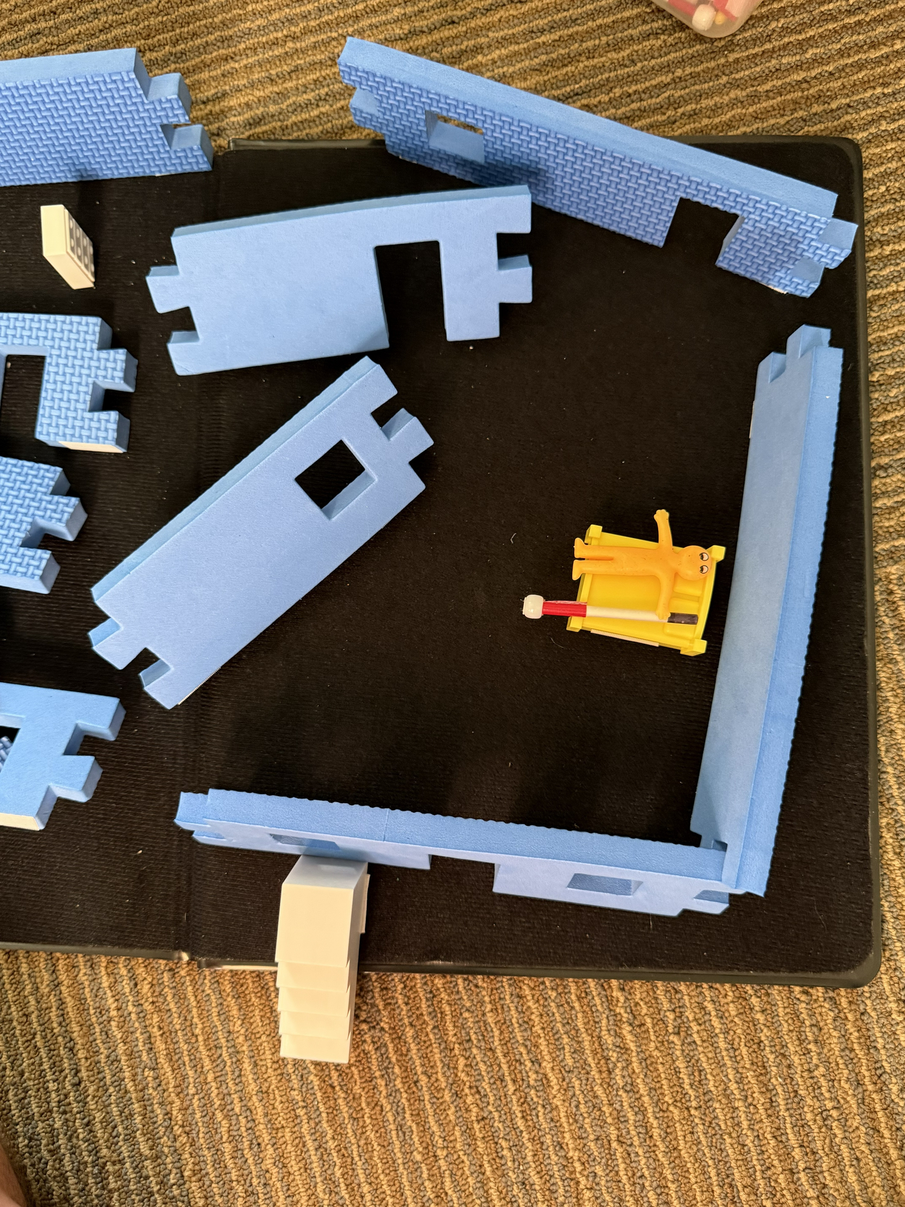 This is an image of a toy called Room with a View. It's some blue foam walls the interlock like puzzle pieces, as well as small pieces of plastic furniture that can go into the house. 