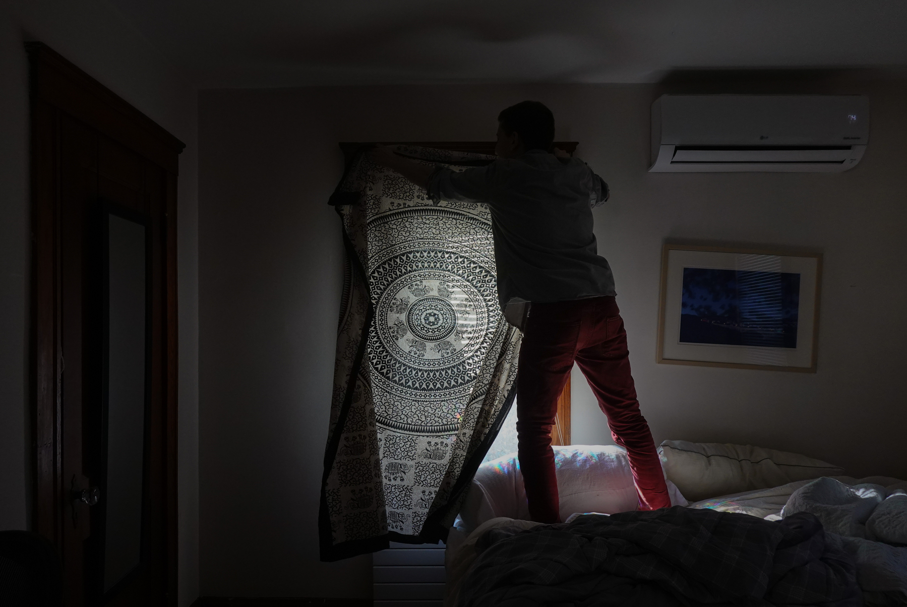 I'm standing on my bed hanging a sheet over the window to block the light