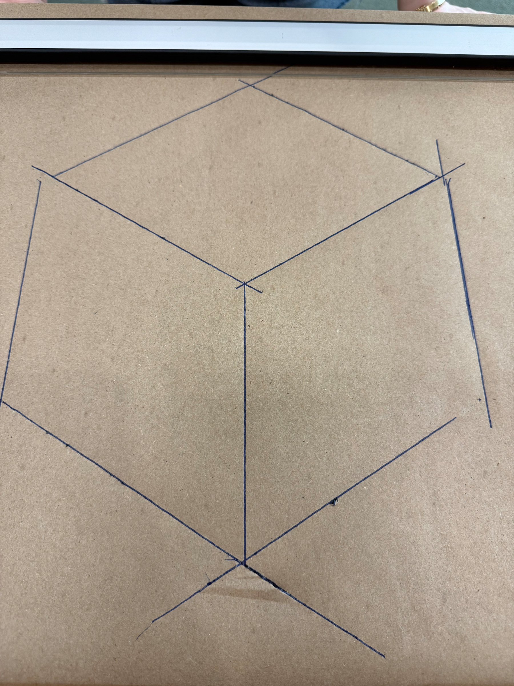 A geometric drawing on brown paper depicts a 3D cube outline formed by intersecting straight lines. It is drawn on a sensational blackboard 
